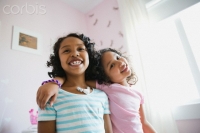 Sisters standing together in bedroom